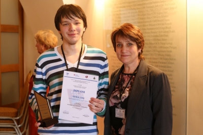 Patrik Žóri z Obchodnej akadémie Rožňava s trofejou a diplomom za 1. miesto v celoštátnej súťaži žiakov stredných škôl v spracovaní informácií na počítači v discilíne Wordprocessing.Vedľa neho stojí Ing. Stanislava Lukáčová, triedna učiteľka V. A, do ktorej chodí aj Patrik.